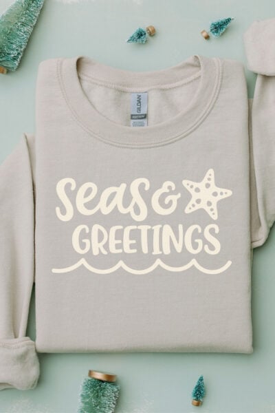 Seas & Greetings Christmas Beach SVG on a gray sweatshirt with Christmas decorations