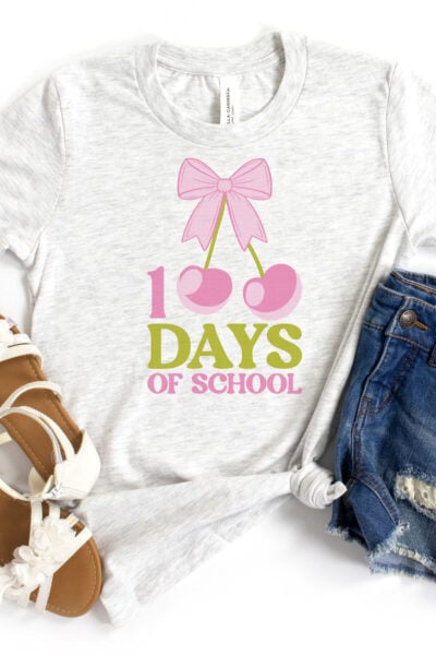 100 Days of School Cherry Sublimation File on a light gray kid's shirt with sandals and shorts with pens in the pocket