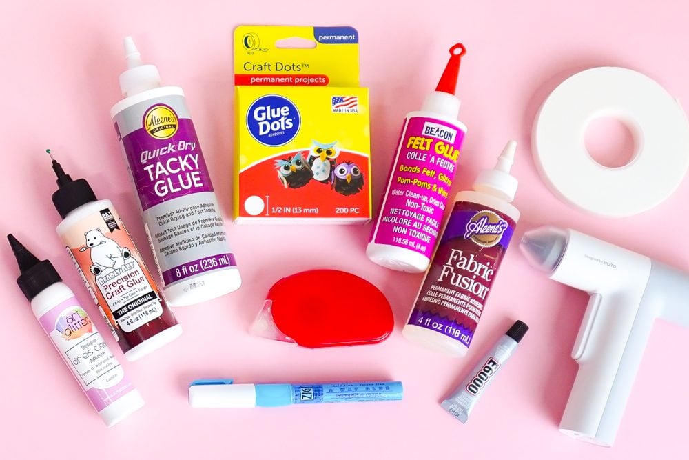 Flay lay of a bunch of different adhesives on a pink table