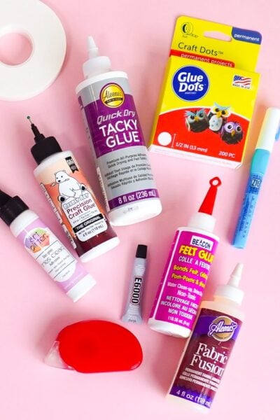 Flay lay of a bunch of different adhesives on a pink table