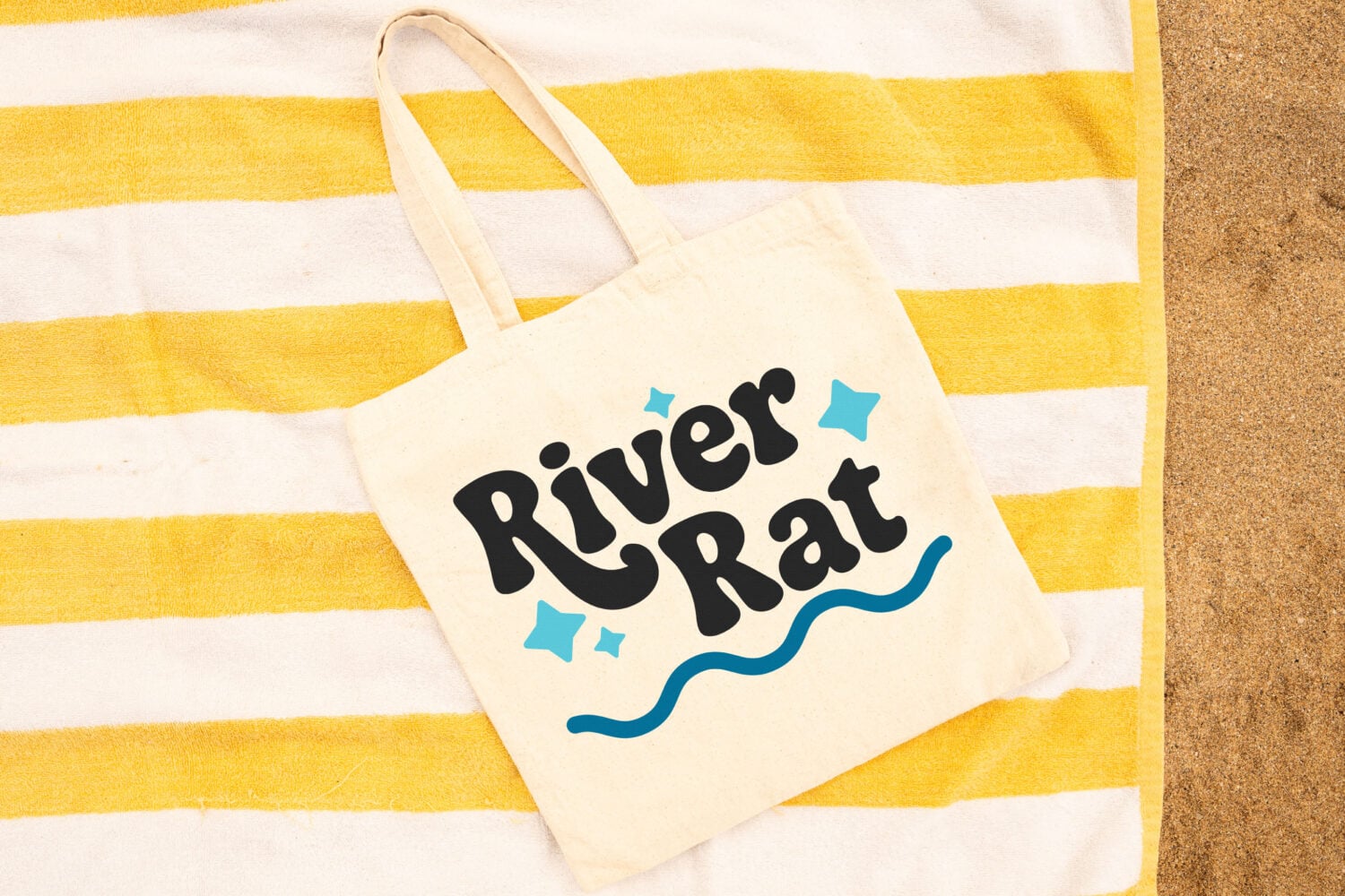 River Rat SVG on a tote bag sitting on a yellow beach towel